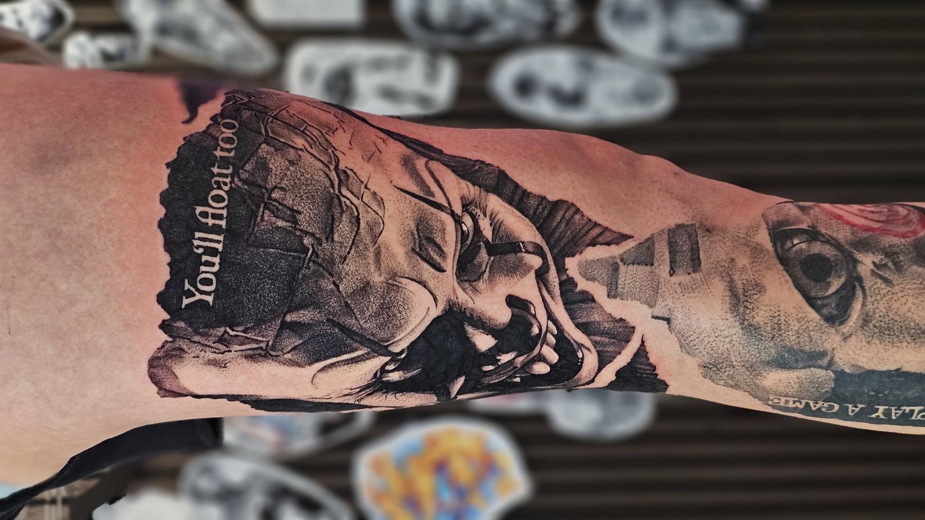 Pennywise aus „Es“ mit „You’ll Float Too“-Schriftzug als Horror-Tattoo – Stiplerealismus Tattoo von Lucas Schenk in Rothenburg bei Luzern